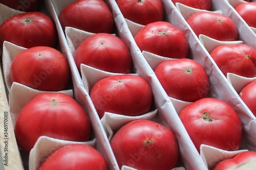 Red ripe tomatoes lie in rows in a box. Concept of delivery and purchase of fresh vegetables and fruits photo