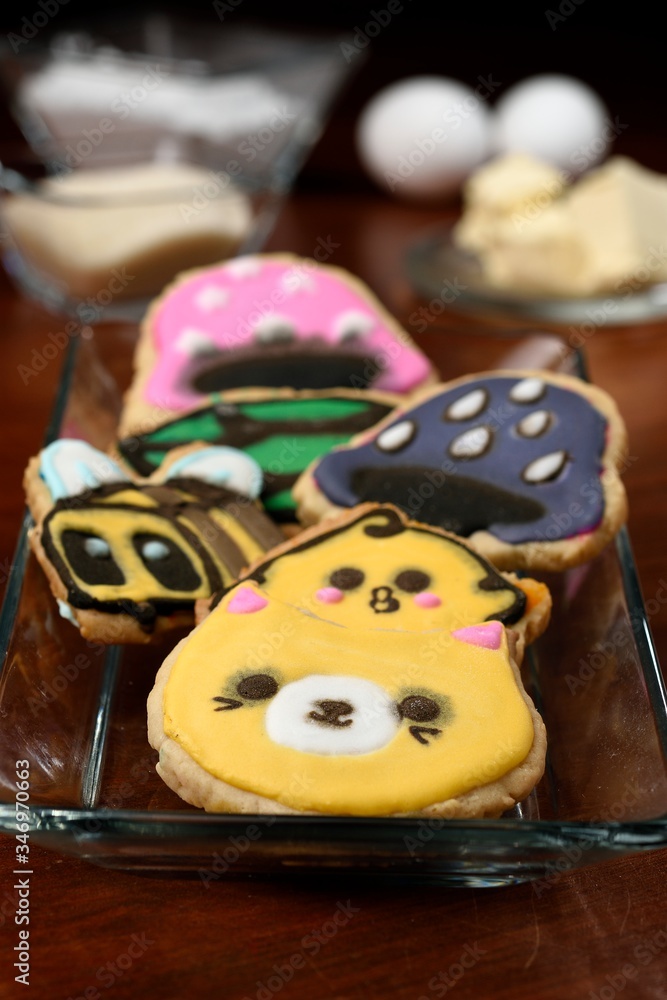 Cookies made with butter and decorated with various figures, in the background in diffuse raw materials for their preparation, mentioning butter, flour, eggs and sugar. Cookies made with butter and decorated with various figures, in the background in diffuse raw materials for their preparation, mentioning butter, flour, eggs and sugar.