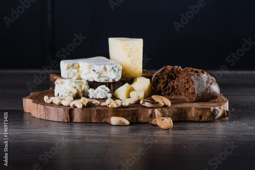 Cheese and bread on a wooden stand on the table dark background. The concept of nutrition and beautiful serving of food.