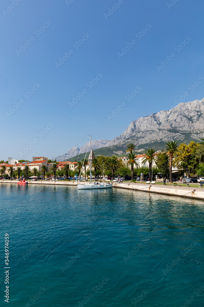 Makarska in Dalmatia, Croatia. View from the sea on a sunny day in the summer. A famous place with beaches and palm trees. Holiday destination at the Mediterranean coast. Relaxing, sunbathing