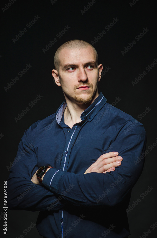 A stylish, bald young man stands on a dark background in the category. Business, Finance A stylish, bald young man stands on a dark background in the category. Business, Finance