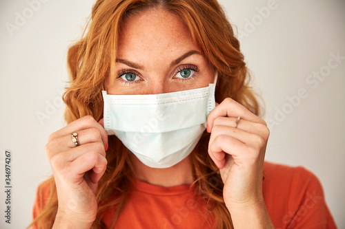 Portrait of red-haired woman wearing a face mask at home photo