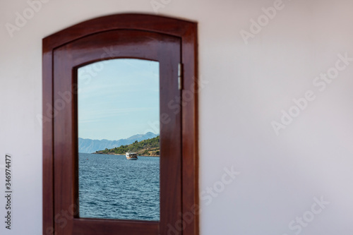 Reflection in a window on board of a boat showing the beautiful view over the Dalmatian Adriatic sea with an island in Croatia on a sunny day. The scenery creates the feeling of holiday and freedom
