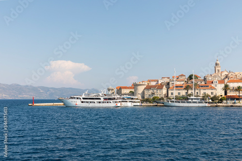Korcula island with the old city walls, view from the sea on a sunny day in the summer blue sky. Clear adriactic sea and cruise ships docked at harbor. The south mediterranean coast of Croatia, Europe