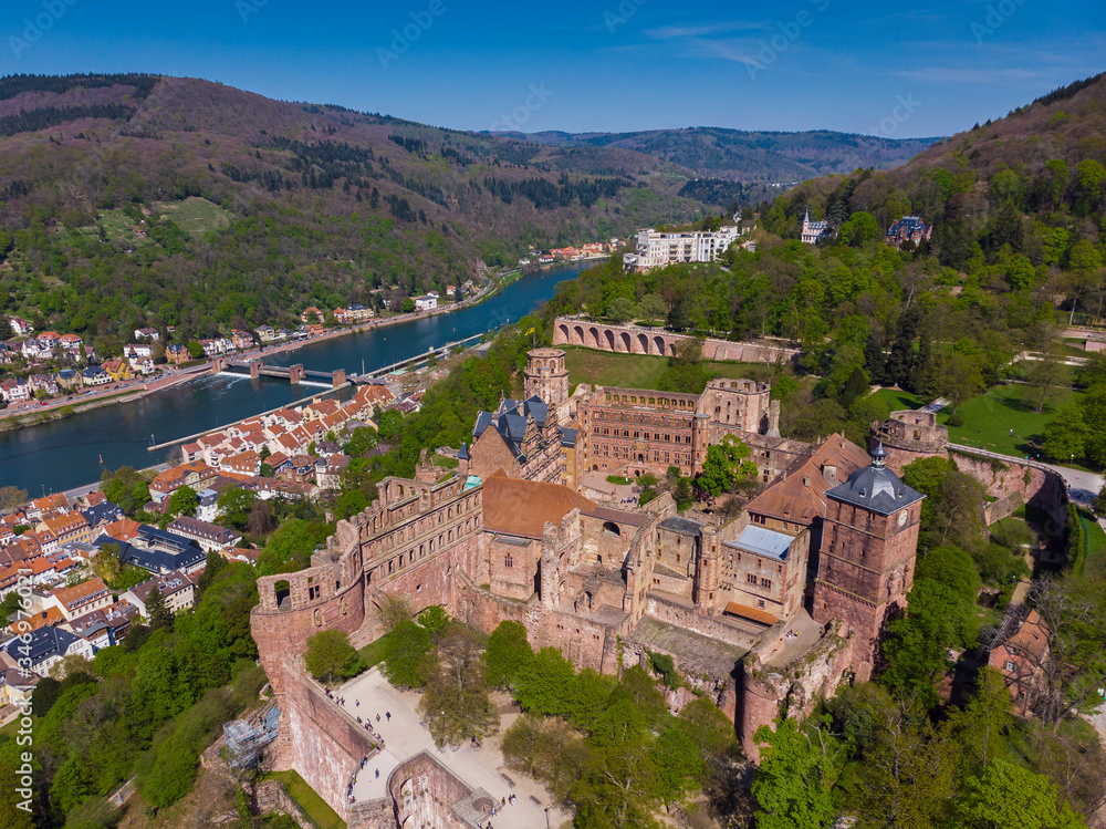 Beautiful top view of the Heidelberg castle and the old part of the city. Spring. Green leaves on the trees. Nekka River. Pedestrian bridge over the river. Beautiful mountains.
