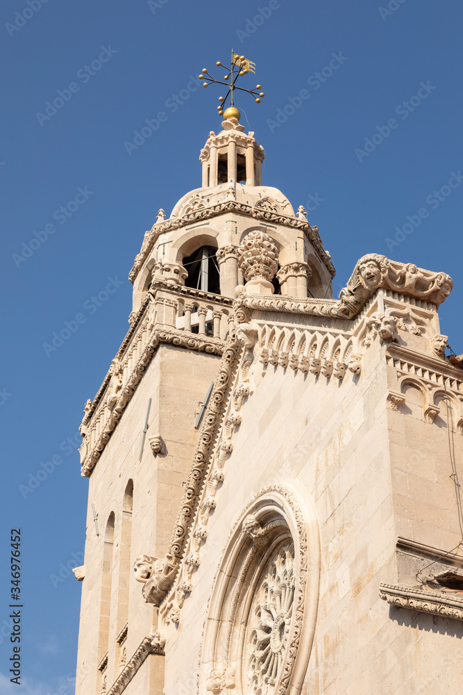 The st Mark church at the town of Korcula island, Dalmatia, Croatia. The beautiful rosette with gothic elements and a blue sky on a sunny day. Old architecture, exterior, facade made of limestone