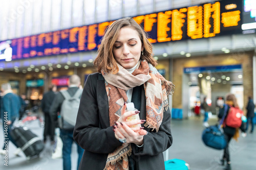 Woman using sanitising hand gel at train station photo
