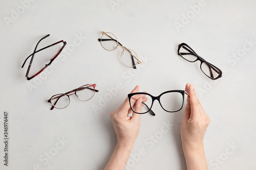 Woman hand holding eyeglasses. Optical store, glasses selection, eye test, vision examination at optician, fashion accessories concept. Top view