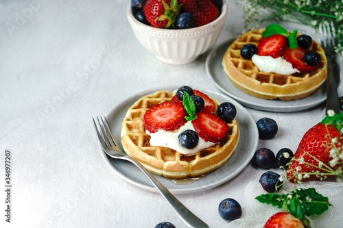 Homemade mini Waffles topped with fresh berries and cream, selective focus