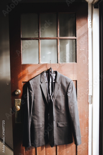 A man's suit for a wedding,celebration,or ceremony hangs on a hanger in the interior. Without man