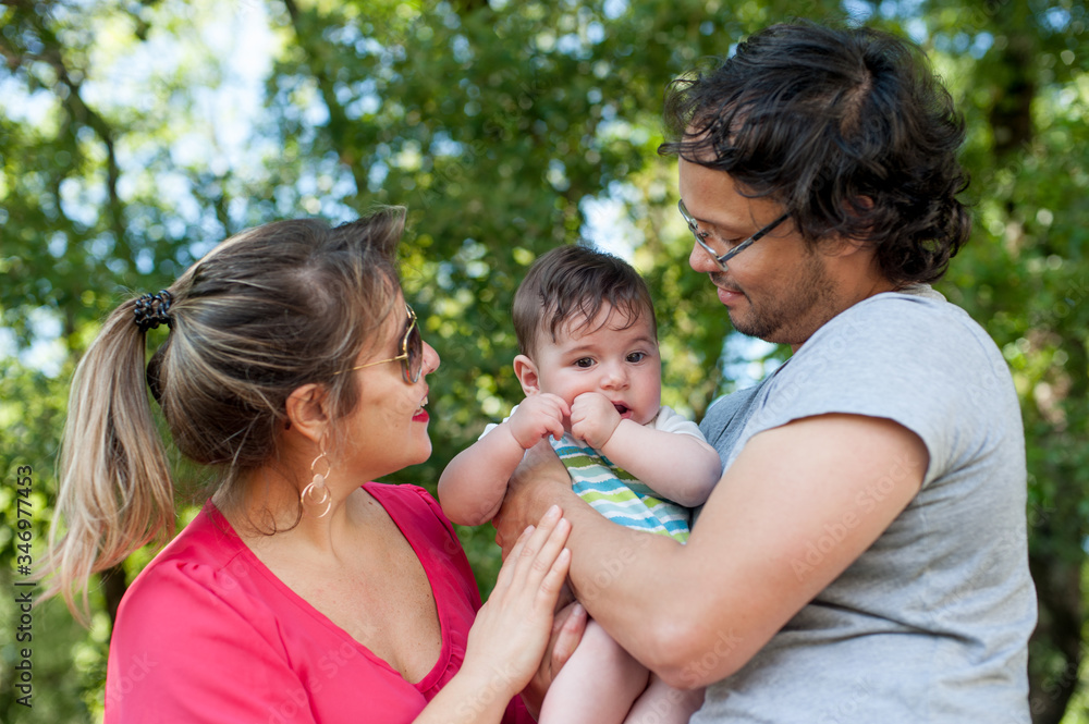 Front view of happy parents playing with their baby in the park. Front view of happy parents playing with their baby in the park.