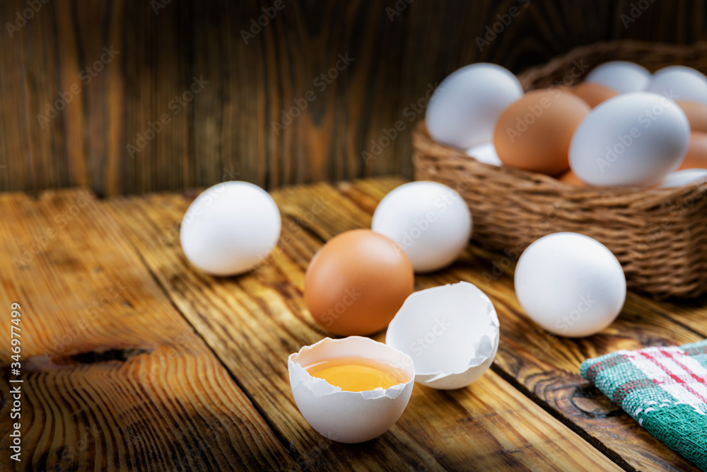 Farm eggs white and brown lie on a wooden table and in a basket, close-up, low light, selective focus, shallow depth of field. Organic food concept Farm eggs white and brown lie on a wooden table and in a basket, close-up, low light, selective focus, shallow depth of field. Organic food concept