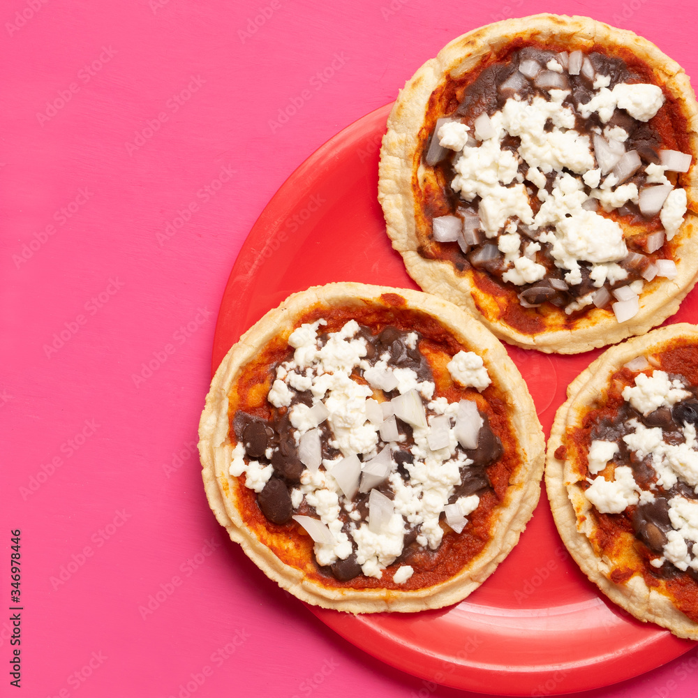 Mexican red sopes with cheese and beans on pink background Mexican red sopes with cheese and beans on pink background