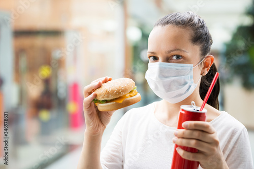 Woman Eating Fastfood Burger In Face Mask
