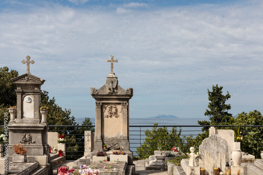 Fototapeta premium Old traditional graveyard, cemetery near the famous mausoleum in Cavtat, small town near Dubrovnik, Dalmatia Croatia. Graves are placed on a hill with view to the sea, mountains, and an island