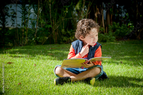 Menino brincando com livro no gramado
