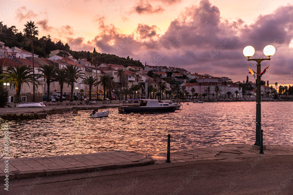 Korcula island shot from the harbour during sunset in summer. Beautiful old venetian town with mountains and a purple sky with deep pink clouds creating an idyllic scenery. Holiday destination