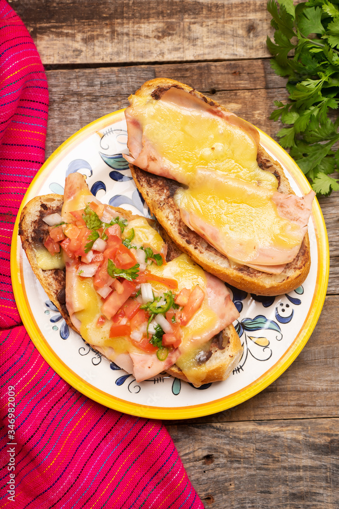 Mexican molletes with ham and cheese on wooden background