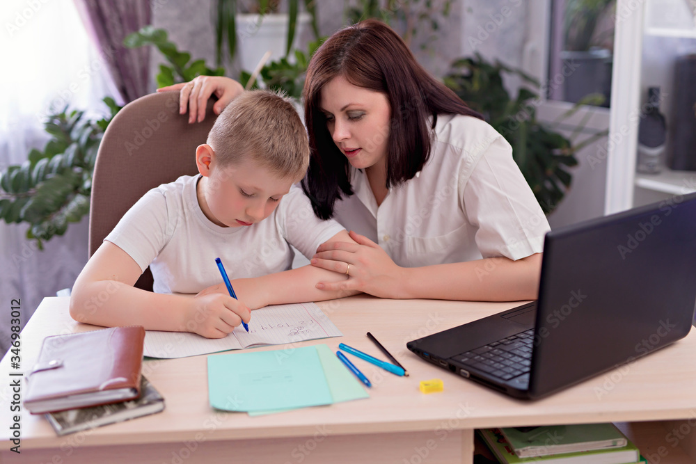 Distance learning, online learning at home during a pandemic. Family mom and son are doing homework in a room on a laptop.