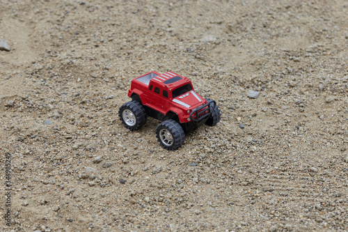 A close up of red toy car jeep in the sand