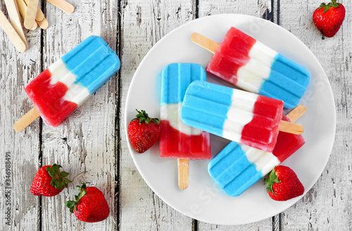 Plate of red, white and blue summer fruit popsicles. Overhead view table scene on a white wood background. photo