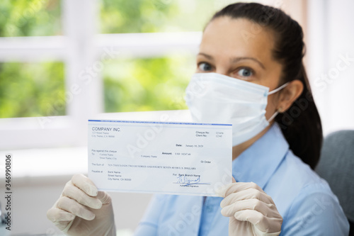 Woman In Face Mask Holding Paycheck photo