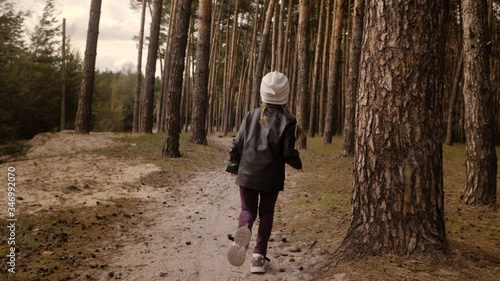 Wallpaper Mural The little girl runs along the path road in the pine forest. Dressed in the leather jacket. Torontodigital.ca