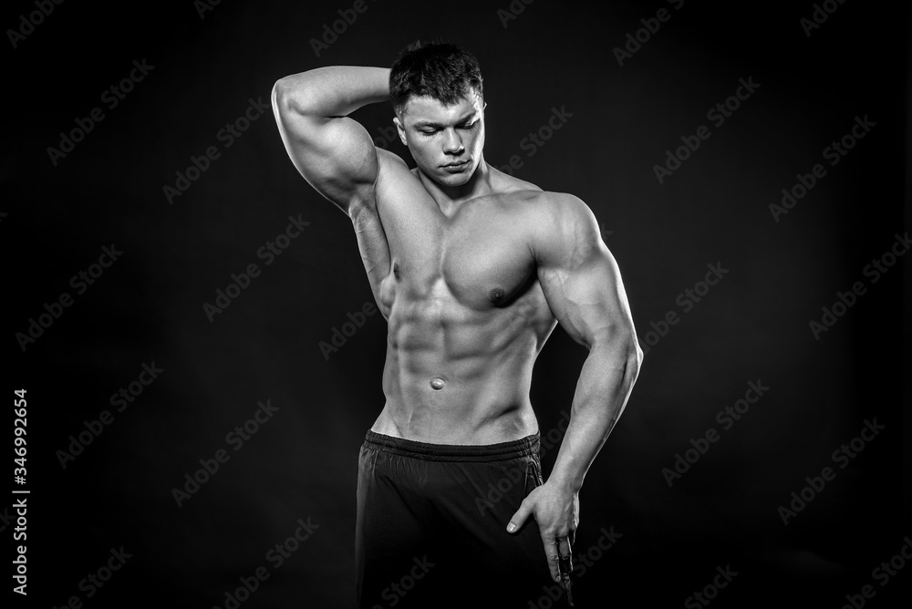 Sexy young athlete posing on a black background in the Studio. Fitness, bodybuilding, black and white Sexy young athlete posing on a black background in the Studio. Fitness, bodybuilding, black and white