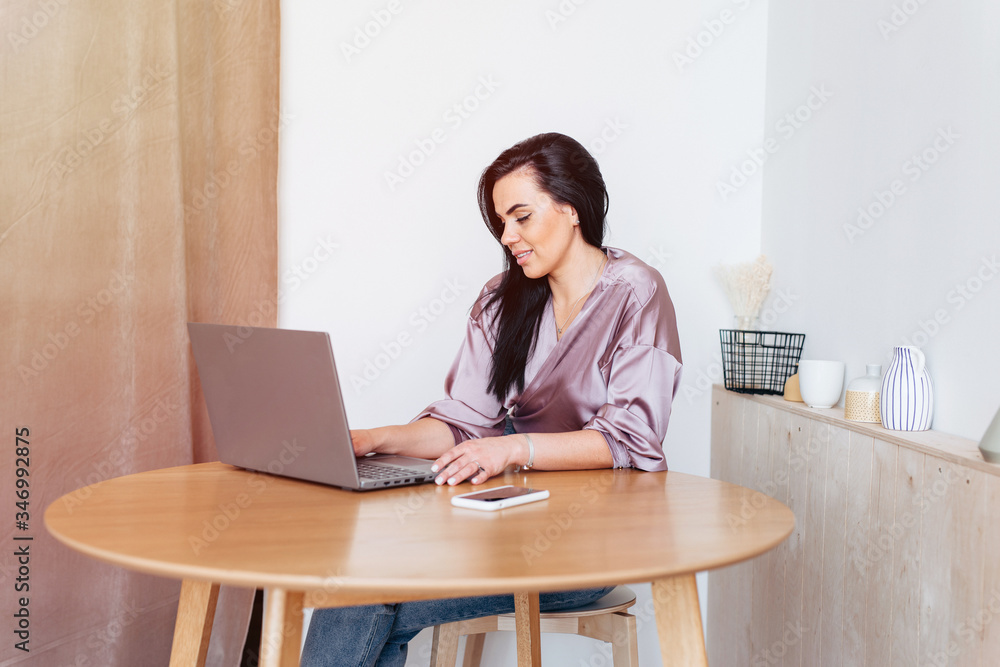 Woman in the kitchen using laptop, working home Woman in the kitchen using laptop, working home