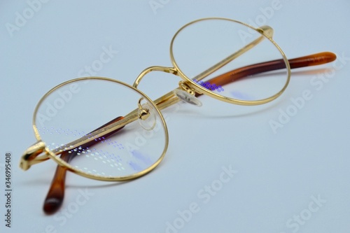Round gold rim glasses on white background