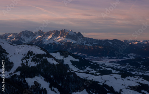 Mountains of mountain range Wilder Kaiser at Fieberbrunn during sunset in winter with snow, forest and valley, clouds in the sky, Tyrol Austria. © Bastian Linder