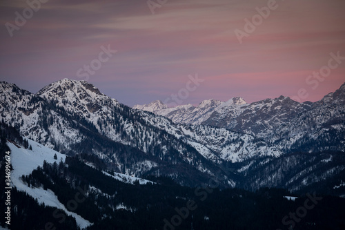 Mountains of mountain range Wilder Kaiser at Fieberbrunn during sunset in winter with snow  forest and valley  clouds in the sky  Tyrol Austria.