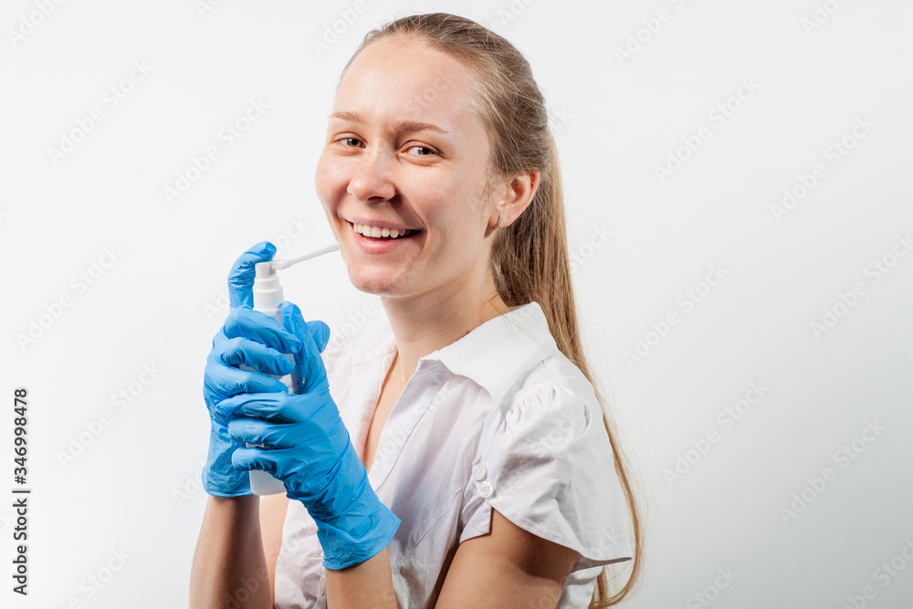 Young and attractive doctor with a throat spray isolated on white Young and attractive doctor with a throat spray isolated on white