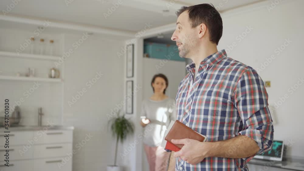 Tilt up of man standing with packed suitcases at home and dreaming of upcoming vacations. Wife showing him sms about flight cancellation on cell phone. Upset man unpacking luggage and hugging wife Tilt up of man standing with packed suitcases at home and dreaming of upcoming vacations. Wife showing him sms about flight cancellation on cell phone. Upset man unpacking luggage and hugging wife