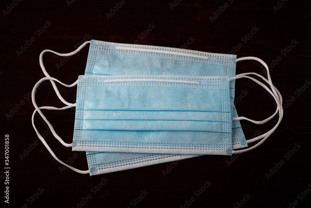 A pack of blue medical masks against a dark background, top view, close up A pack of blue medical masks against a dark background, top view, close up