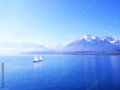2 sailing boats towards snow mountain 