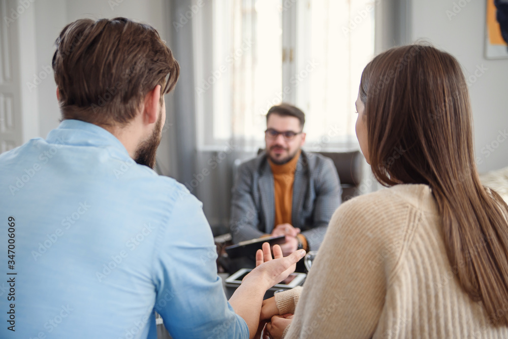 Young unhappy couple on special marriage therapy session with professional therapist. Qualified psychologist listen family problems of young unhappy couple. Young unhappy couple on special marriage therapy session with professional therapist. Qualified psychologist listen family problems of young unhappy couple.