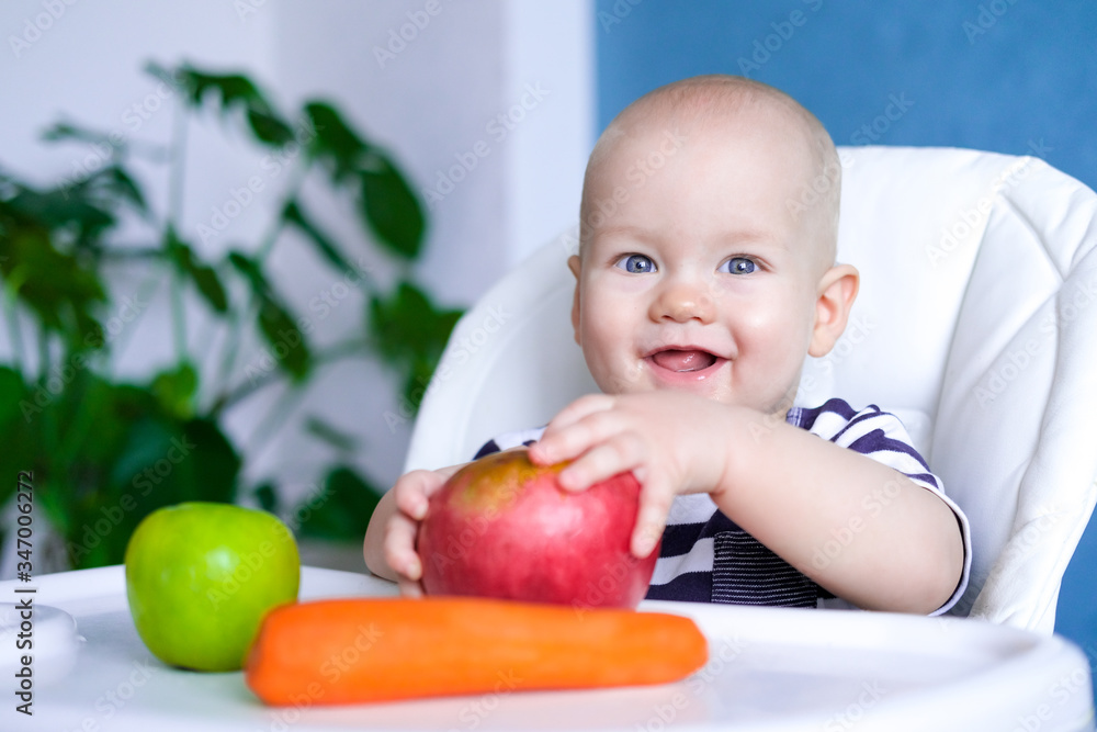 baby food. Little smiling caucasian child with big red Apple and carrot on highchair. healthy food. Fresh vegetables and fruits. New born infant kids. baby food. Little smiling caucasian child with big red Apple and carrot on highchair. healthy food. Fresh vegetables and fruits. New born infant kids.
