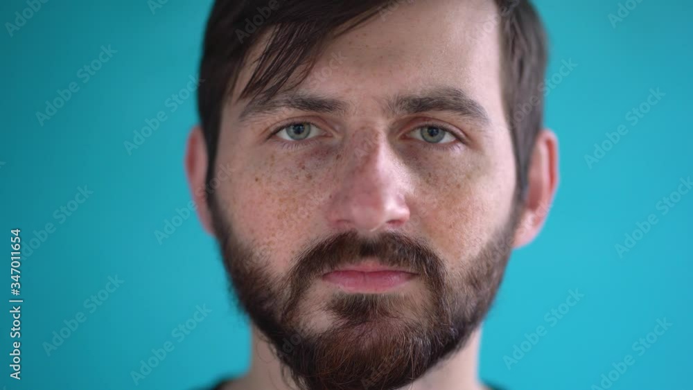 Portrait of wonderful man close up. Bearded brunet doctor with green eyes take off protective medical face mask isolated on blue background. State of emergency. Quarantine during a pandemic by virus Portrait of wonderful man close up. Bearded brunet doctor with green eyes take off protective medical face mask isolated on blue background. State of emergency. Quarantine during a pandemic by virus
