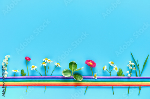 Thank you doctors and nurses! Rainbow ribbon covering various Spring flowers, primrose, chamomile, lily of the valley Creative flat lay on blue mint background with copy-space photo