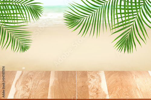 Fototapeta Naklejka Na Ścianę i Meble -  Wood table top on blurred beach background with green palm leaf, summer concept
