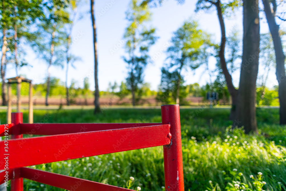 in the  foreground is a metallic construction in light red the background is filled with pure nature