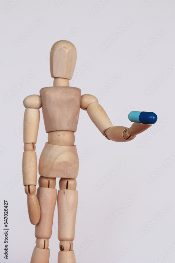 Blue capsule medicine held by wood figurine Blue capsule medicine held by wood figurine