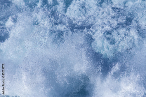 Aquatic background of sea surf waves splashing close up with clear blue green water and white foam