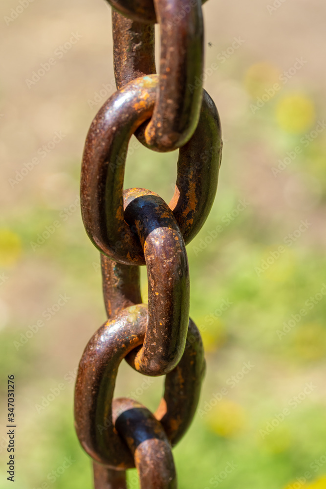 Metal rusty chain close-up, unfocused background of nature. Metal rusty chain close-up, unfocused background of nature.