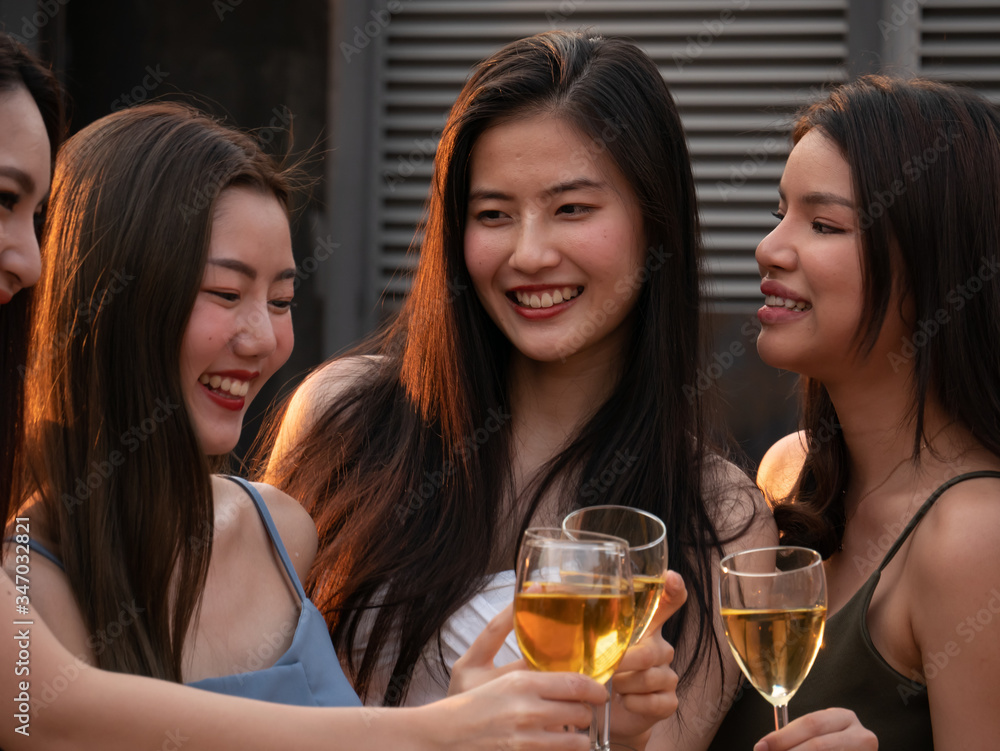 Group of asian friend cheering and drinking at terrace party. Young people toasting glass with wine at rooftop restaurant. Friendship ,youth lifestyle and nightlife concept.