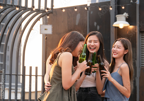 Group of asian friend cheering and drinking at terrace party. Young people enjoying and hanging out on rooftop at sunset. Friendship ,youth lifestyle and nightlife concept.