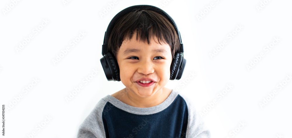 Family, home, technology and music concept. Portrait Young little Asian boy listening music with headphones at home. School child listening loud music in wireless earphones