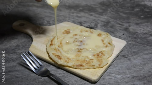 Roti and sweetened condensed milk on a wooden table, roti cananai or roti, knead the dough by roti with oil Traditional Indian street food, handmade roti
