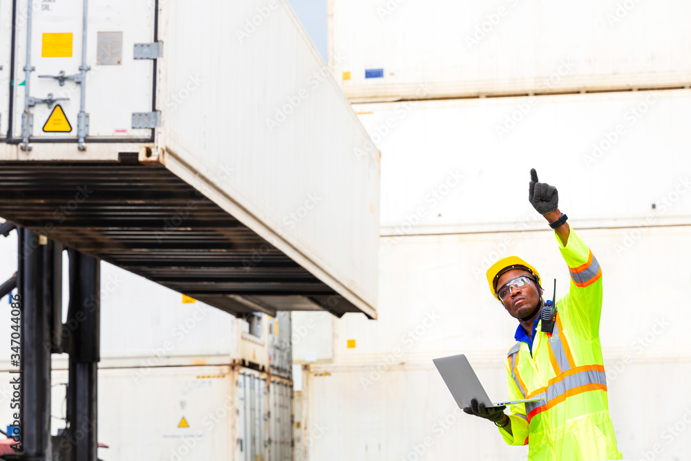 Looking forword. Foreman using laptop computer in the port of loading goods. Foreman showing thumbs up on Forklifts in the Industrial Container Cargo freight ship.